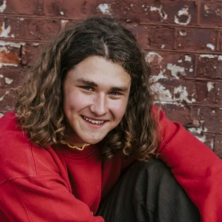 lächelnder junger Mann mit rotem Pullover